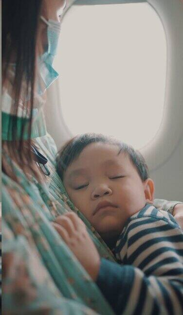 乘飞机旅行时男孩睡在母亲的怀里