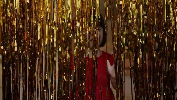 身穿红色连衣裙的韩国女孩在圣诞夜用金箔装饰玩耍