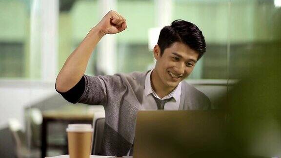 年轻的亚洲商人庆祝在办公室的成功