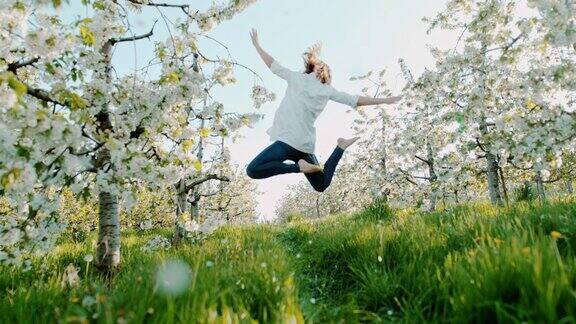 一个狂喜的女人在樱花花丛中跳跃