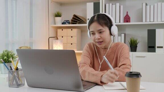 年轻的亚洲女孩在家里通过在线课程学习并在笔记本电脑上与老师聊天