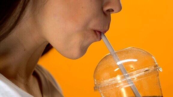 口渴的女孩喝冷汽水从塑料杯与吸管近