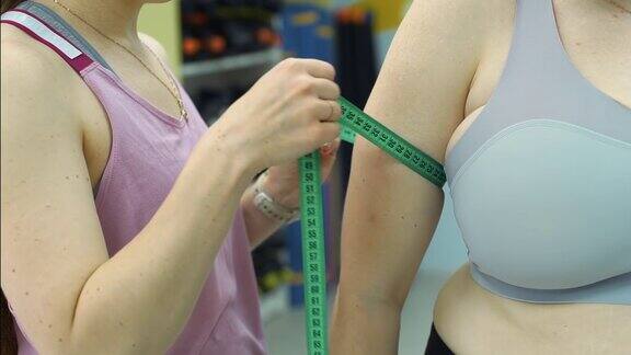 健身教练测量超重妇女的手臂
