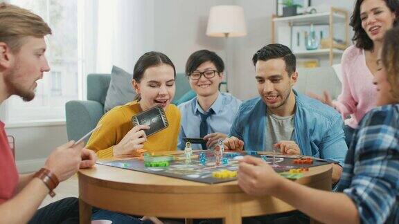 不同的群体的男孩和女孩玩在一个战略棋盘游戏与纸牌和骰子白天舒适的客厅