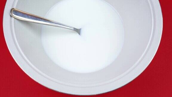 碗美味的酸奶和勺子在红色背景特写