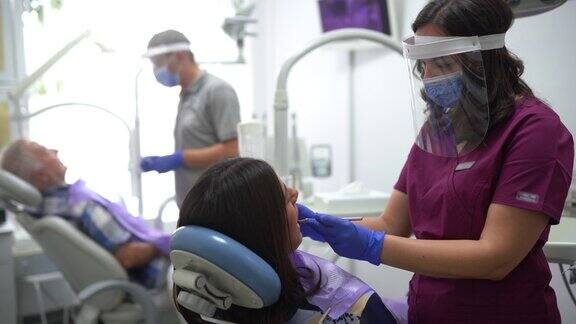 两名牙医在牙医办公室合作采取冠状病毒安全措施