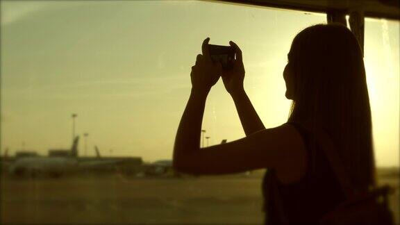 女孩们在用手机拍摄飞机和跑道的照片剪影风格