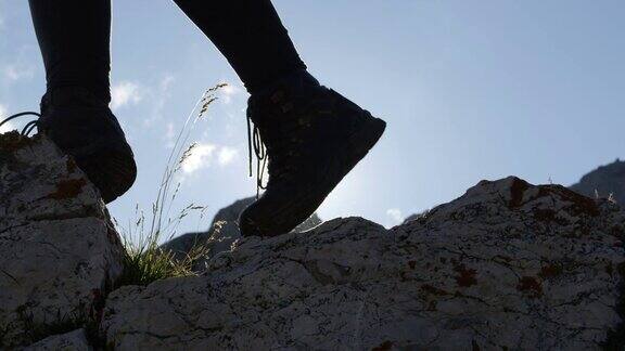低角度:皮革山鞋和女性攀登陡峭的山的细节
