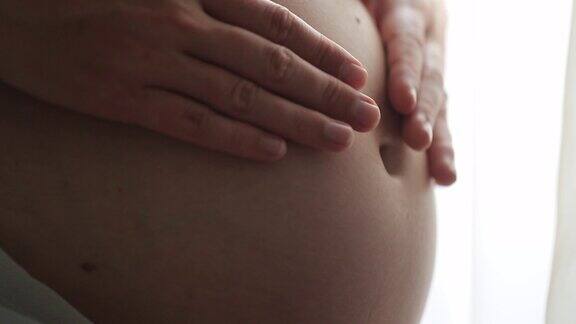 孕妇的手抚摸肚子的宏观特写