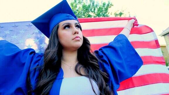 年轻女子举着美国国旗庆祝毕业