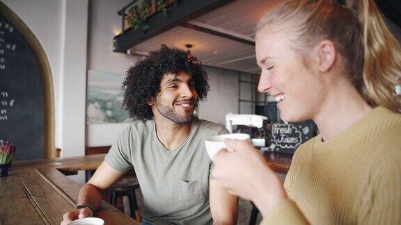 一个快乐的男人在咖啡馆喝咖啡的时候和她的女性朋友分享这个消息