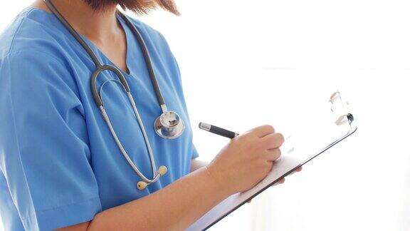 女医生用蓝色制服在写字板上写字