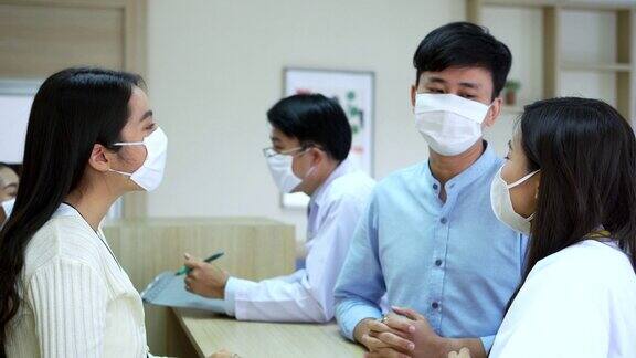 亚洲男性患者戴着医用口罩在现代医院大堂向女医院前台和专业医生询问治疗信息医院和医疗保健理念