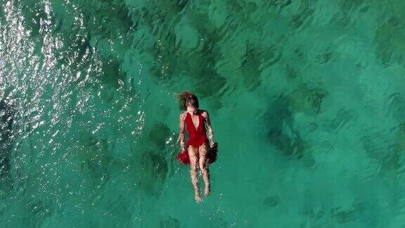 一个女人在热带海洋上漂浮和游泳的无人机视图