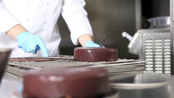 手糕点厨师准备蛋糕盖倒巧克力糖霜工作在不锈钢工业厨房工作顶部