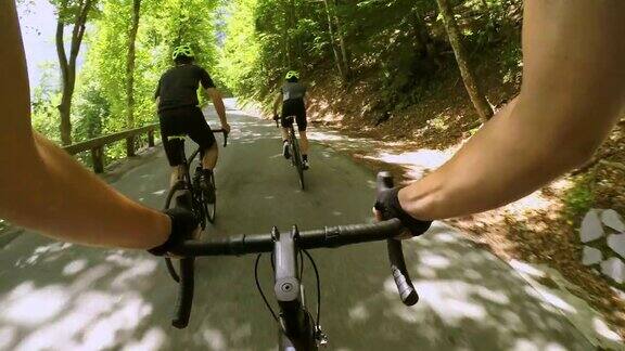 在阳光明媚的山路上一名骑自行车的男子被两名骑自行车的男子超越