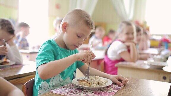 幼儿园的小男孩用叉子吃排骨