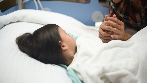 生病的小女孩睡在医院的床上由她的妈妈照顾
