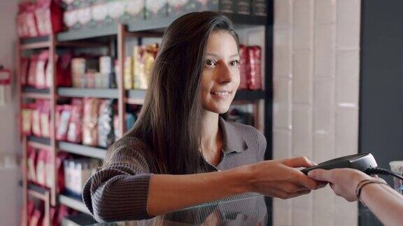 这位漂亮的年轻女士在咖啡厅用信用卡付账按下按钮