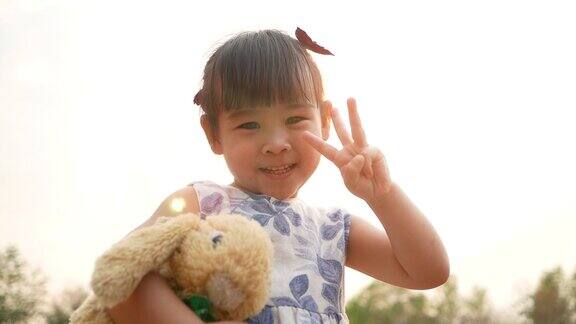 可爱的亚洲小女孩抱着泰迪熊在公园感觉爱