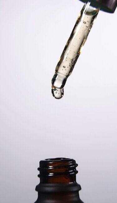 垂直镜头:液滴从移液管中以中心位置落进瓶子中的慢动作