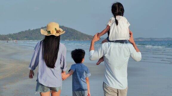 幸福的一家人在海滩上散步快乐的一家人在海滩上享受暑假假期iStock