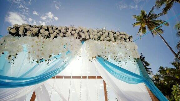 热带海滩上的婚礼拱门装饰着鲜花和大型迎风织物在运动菲律宾保和