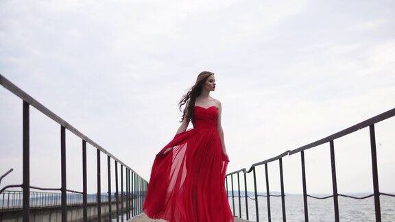 一个年轻浪漫的女人穿着红色长裙站在码头上