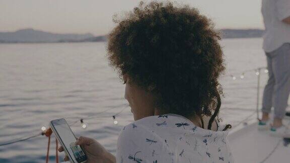 一名年轻女子在帆船的甲板上使用她的智能手机