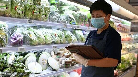 一位亚洲华人超市店主戴着口罩的零售助理