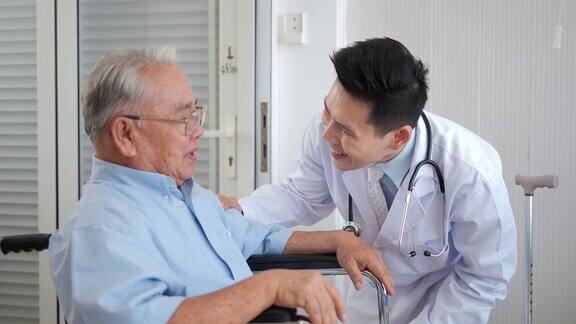 亚洲男子医生帮助支持坐在轮椅上的残疾老人医生护工或护士协助照顾微笑的残疾老人祖父老年人的保健理念