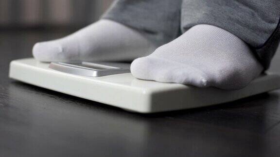 肥胖男子在健康秤上测量自己的体重节食和减肥特写