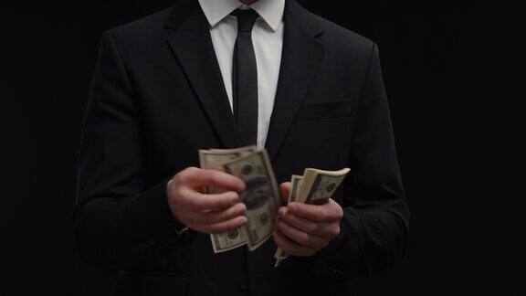 一名男子金融顾问身穿黑色西装从口袋里掏出钱来数钞票管理的业务影子投资者计算美元钞票现金利润