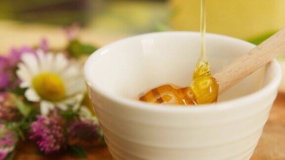 白色的碗里甜美的蜂蜜流在木勺轴上采集新鲜的蜂蜜健康环保的天然糖食品养蜂和收获