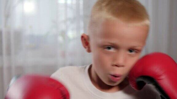 一个戴着拳击手套的小男孩在家练习出拳的特写镜头