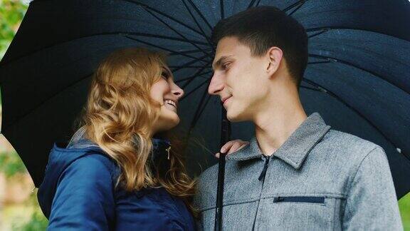 一对年轻漂亮的夫妇站在伞下下雨了