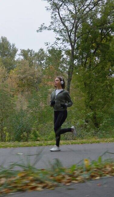 竖屏:秋天慢动作女子在森林中慢跑