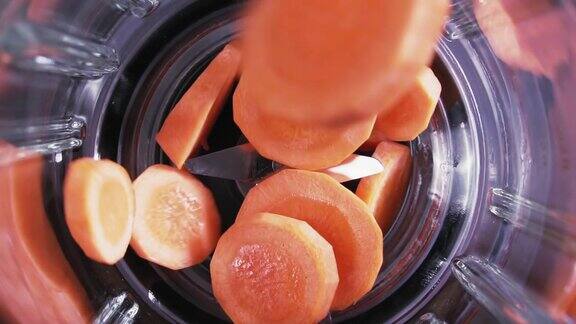 胡萝卜片落入搅拌机慢动作橙汁在搅拌机里俯视图健康饮食