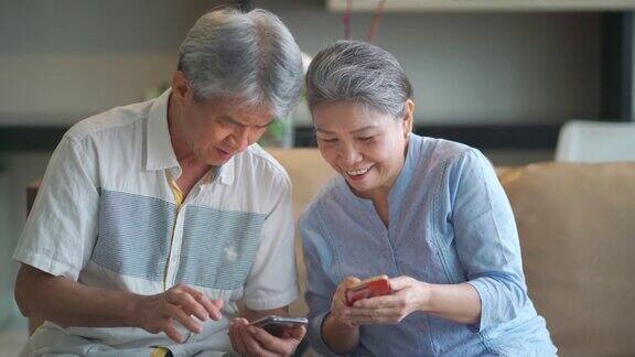 快乐的亚洲华人祖父母使用电话在客厅愉快地交谈