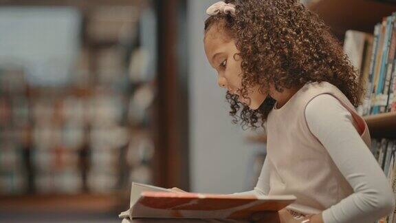 一个小女孩独自在图书馆里小孩子在做研究可爱的孩子在图书馆做作业