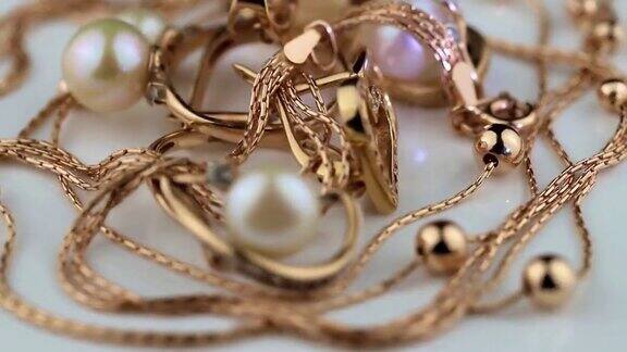 镶有宝石和珍珠的金耳环和戒指在白色的表面上旋转