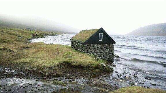 在法罗群岛的海边屋顶覆盖着苔藓的小屋的风景