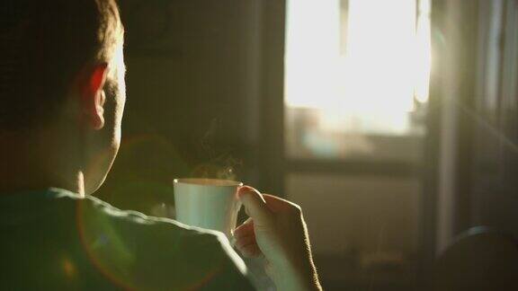 在日出的背景下一个男人的剪影与一杯热咖啡