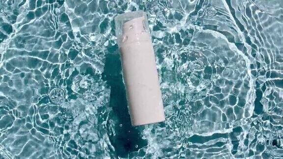 化妆品瓶油瓶液体瓶胶原蛋白血清落在水中溅在蓝色背景缓慢的运动女性化妆品护肤包装美容产品布局样本