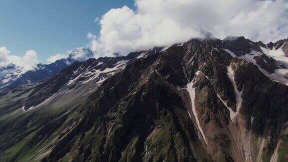 陡峭的岩石山脉有悬崖和壁架覆盖着雪和云