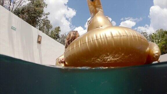 金发女孩放松在充气黄金天鹅在墨西哥人们旅游豪华酒店年轻女子在游泳池里晒日光浴慢动作