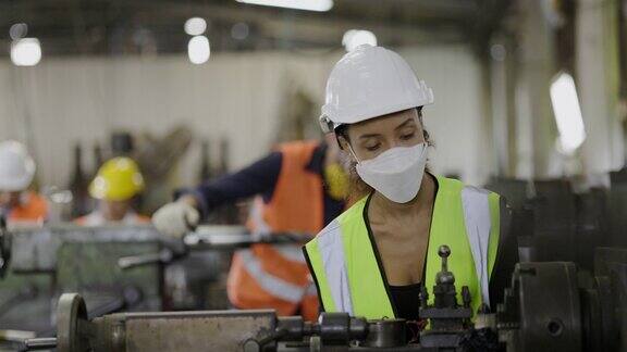 工业工厂机械师在工业工厂与机器一起工作时要戴口罩、安全帽减少COVID-19和粉尘PM2.5的风险机器检查服务技术人员