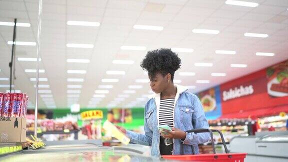 一位女士正在超市购物并用智能手机扫描条形码