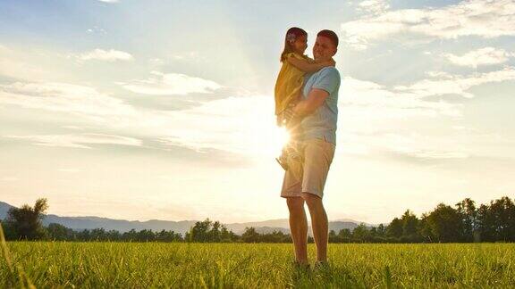 父亲抱着他的小女儿在阳光灿烂的草地上