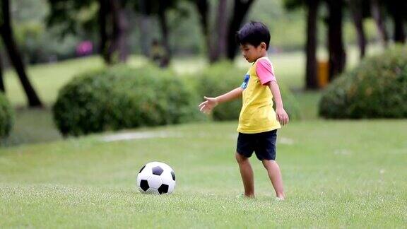 一个亚洲小男孩在公园里踢足球